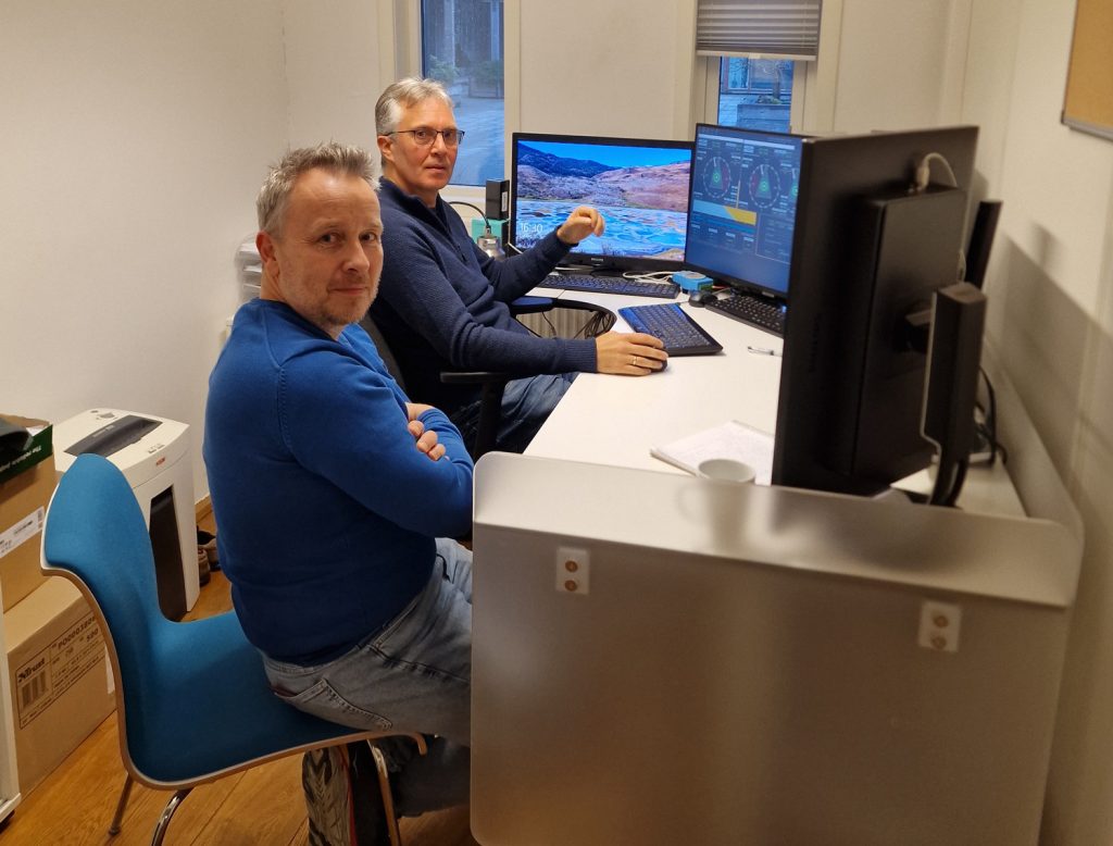 a group of men sitting at a desk with computers